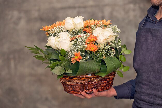 バスケットの中の花の花束を促進する男性の花屋。