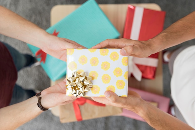 Male friend's hand holding gift box with golden ribbon bow