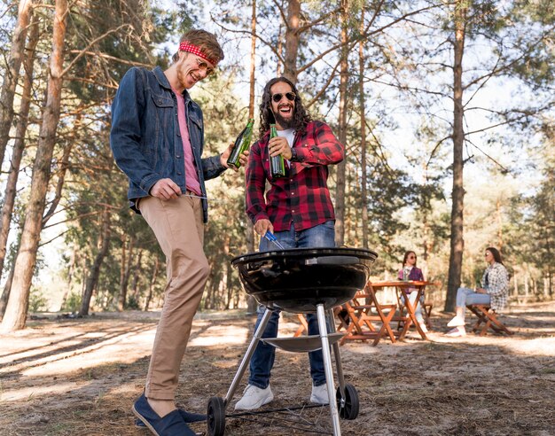 Amici maschi che bevono birra sopra il barbecue