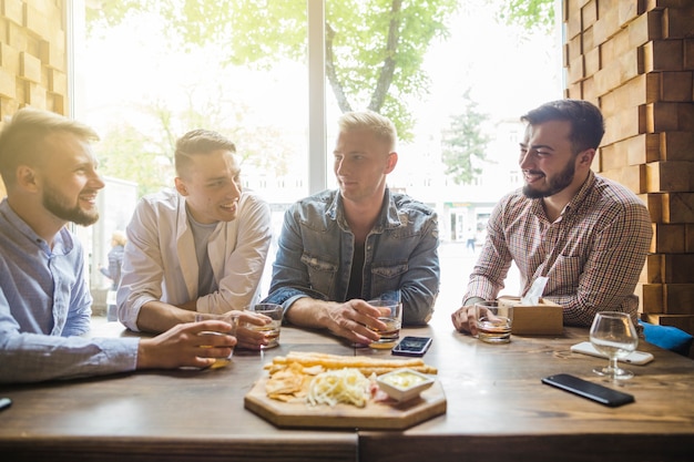 Male friends enjoying the drinks with snack in the restaurant