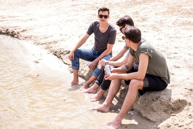 男性の友達がビーチに座りながら夏を楽しんで