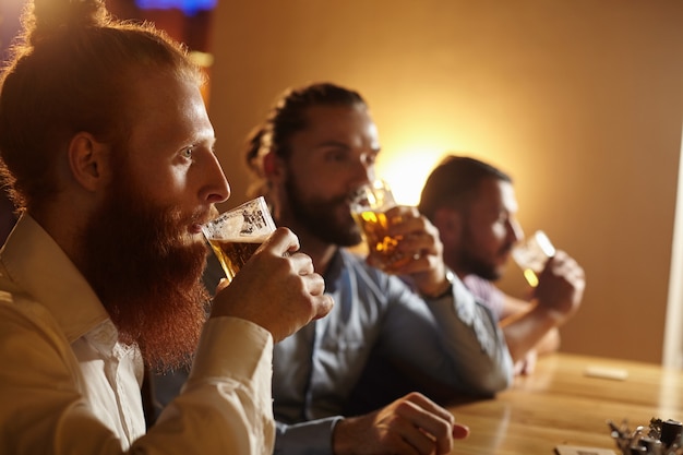 Foto gratuita amici maschi che bevono una birra al bar