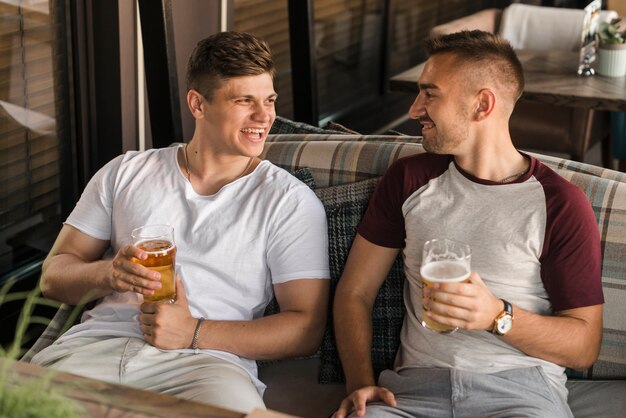 Male friends holding glasses of bear enjoying