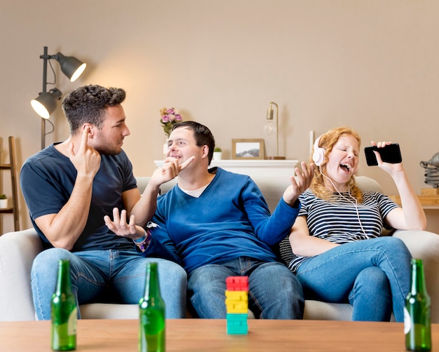 Male friends laughing at woman for singing with headphones on