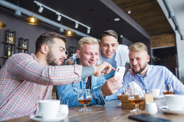 Male friends looking at cellphone sitting in the restaurant