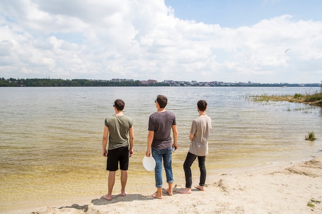 Male friends standing looking at river