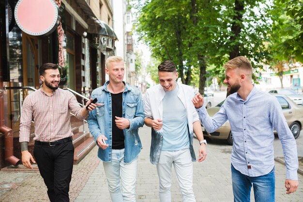 Male friends walking together on city street enjoying