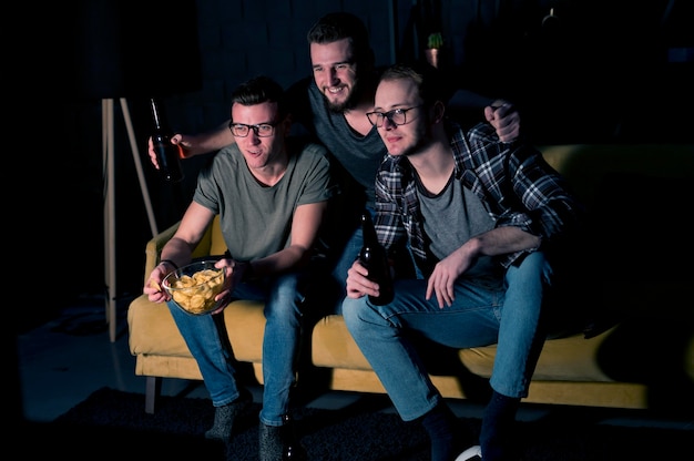 Free photo male friends watching sports on tv together with snacks