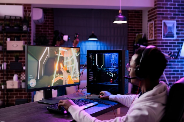 Мужчина-геймер, играющий в видеоигры онлайн на компьютерной станции, наслаждаясь многопользовательской игрой в киберспортивном турнире. Молодой человек транслирует чемпионат по геймплею в качестве досуга.