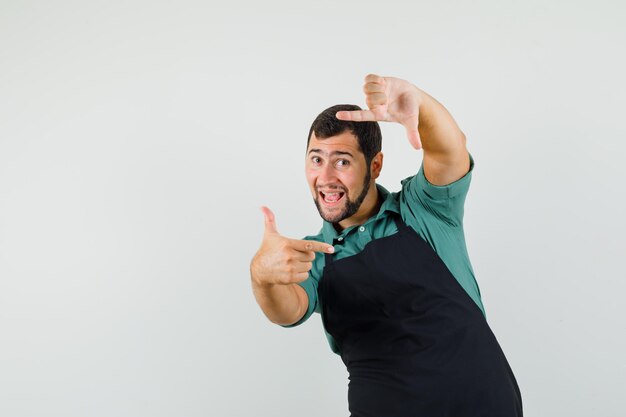 Male gardener in t-shirt, apron making frame gesture and looking cheerful , front view.