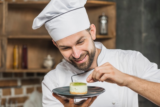 Male garnishing delicious dessert on plate