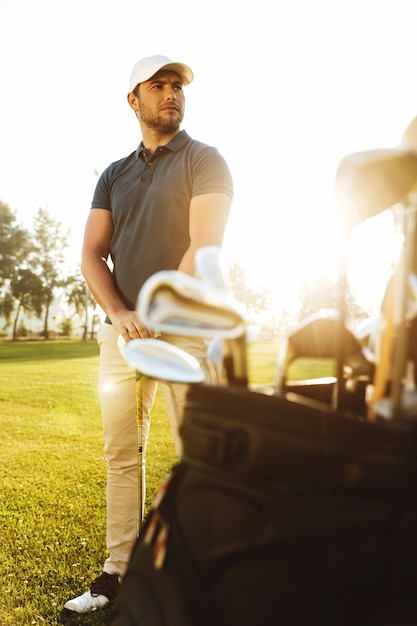 Foto gratuita giocatore di golf maschio al corso verde con un sacco di club