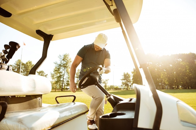 Foto gratuita giocatore di golf maschio che ottiene in un carrello di golf