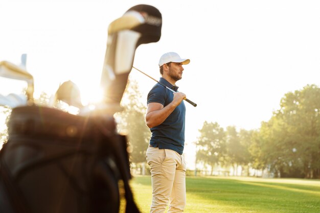 Мужчина гольфист держит водителя стоя
