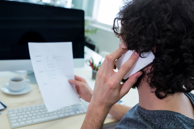 Male graphic designer talking on mobile phone