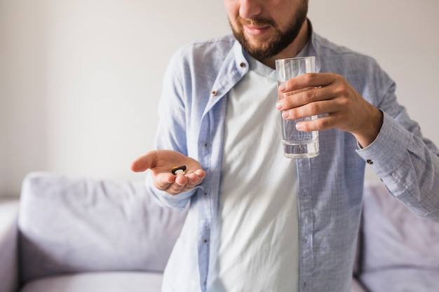 Male in grey will pills and glass of water