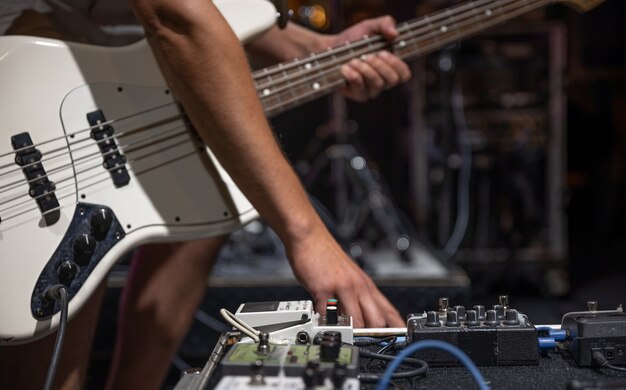 A male guitarist setting up guitar audio processing effects on stage.