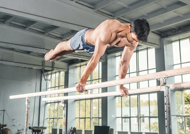 Male gymnast performing handstand on parallel bars