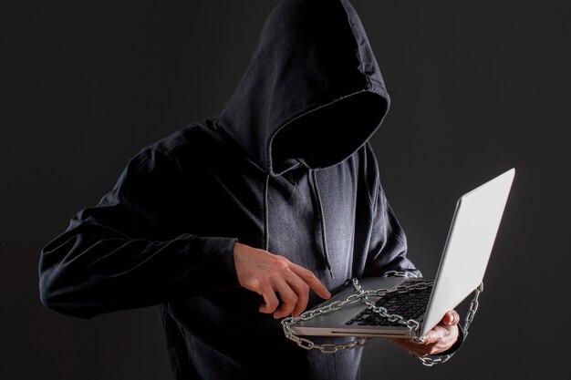 Male hacker with laptop protected by chain