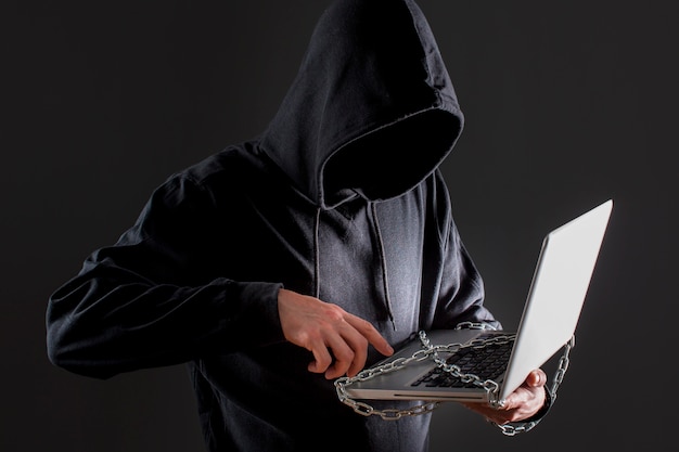 Мужской хакер с ноутбуком защищен цепью
