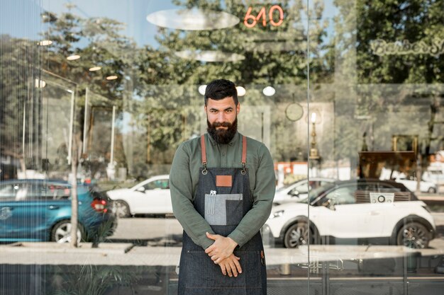 Male hairdresser standing near barbershop with glass walls