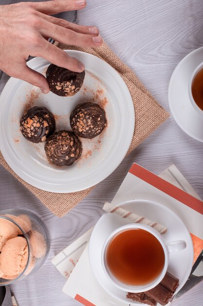 男性の手がテーブルからチョコレート菓子をキャッチします。本、お茶、トップビュー