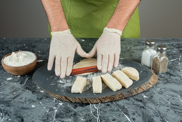 Мужская рука в перчатках, делая тесто на мраморном столе.