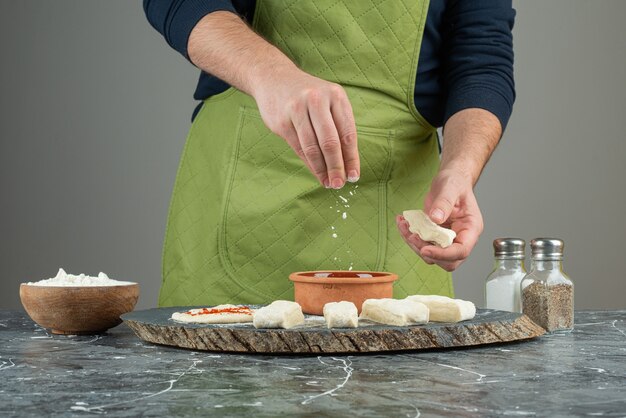 Male hand in gloves making dough on marble table.