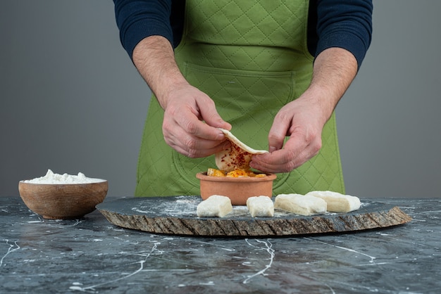 Mano maschio in guanti che producono cibo sul tavolo di marmo.