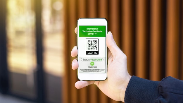 Бесплатное фото Мужская рука держит смартфон с qr-кодом международного сертификата вакцинации covid-19