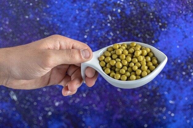 Free photo male hand holding bowl of green peas