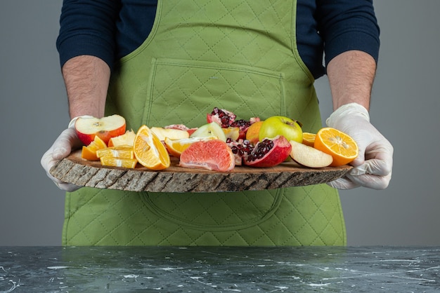 Mano maschio che tiene il mazzo di frutta fresca sul tavolo di marmo.