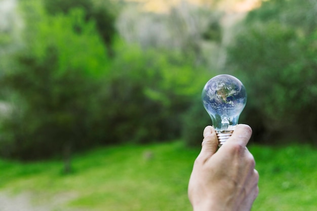 Male hand holding Earth in glass bulb