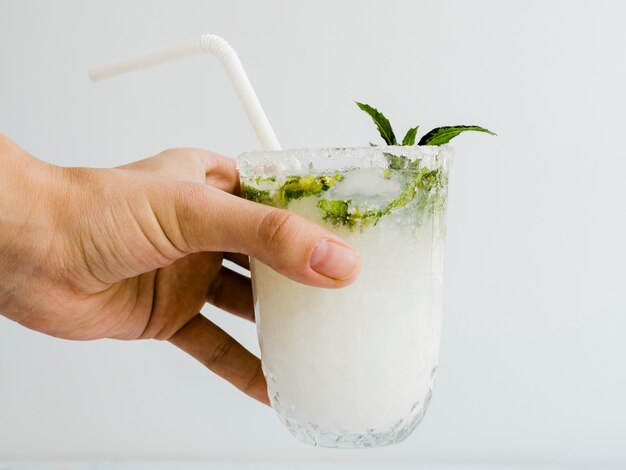 Male hand holding glass of cocktail with peppermint and straw