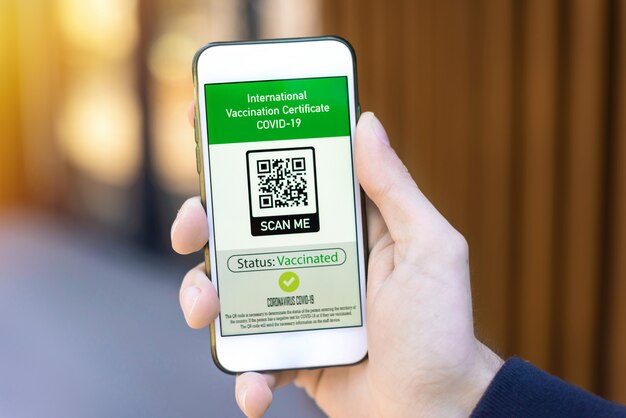 Мужская рука держит смартфон с QR-кодом международного сертификата вакцинации COVID-19