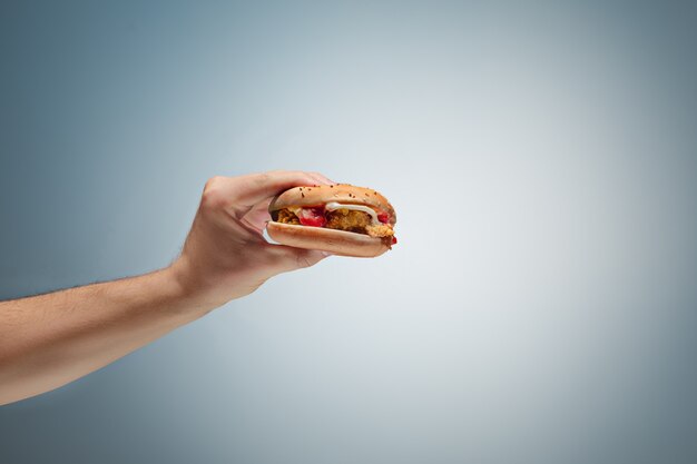 Male hand holding tasty hamburger