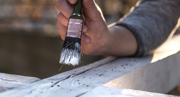 男性の手が木材、絵画の概念、クローズアップ、テキストのための場所に白いペンキで塗料します。
