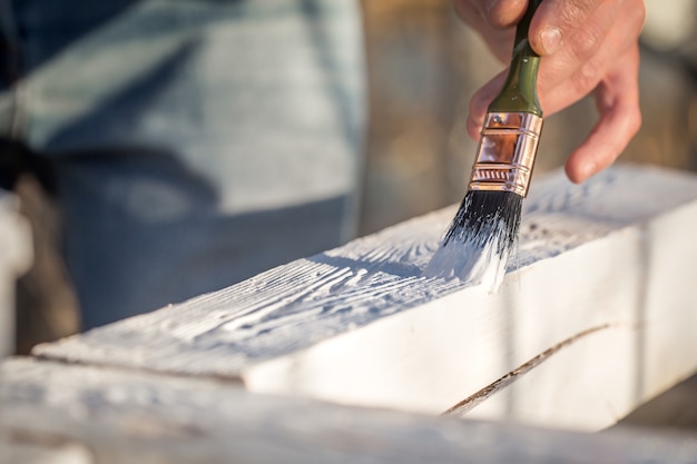 男性の手が木材、絵画の概念、クローズアップ、テキストのための場所に白いペンキで塗料します。