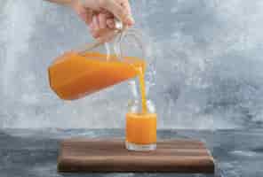 無料写真 ガラスにオレンジジュースを注ぐ男性の手。