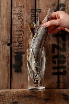 Male hand taking out airdried salted sabrefish from glass