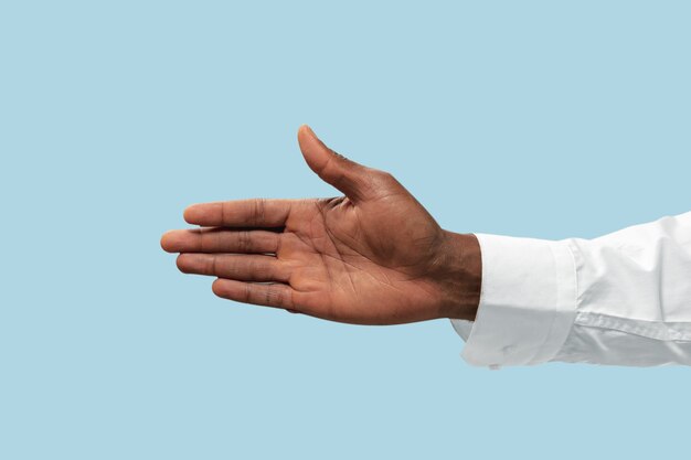 Male hand in white shirt demonstrating a gesture of inviting or pointing isolated on blue.