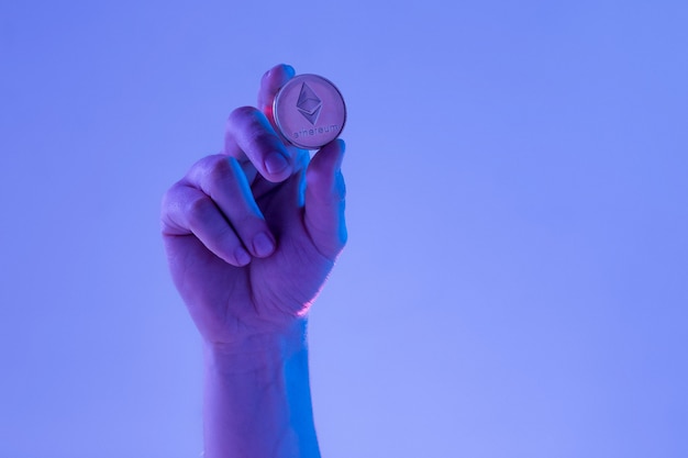 Male hand with golden Ethereum on blue background