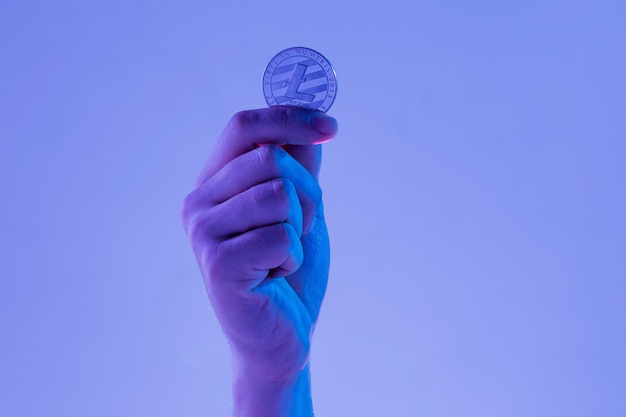 Free photo male hand with golden litecoin on blue background