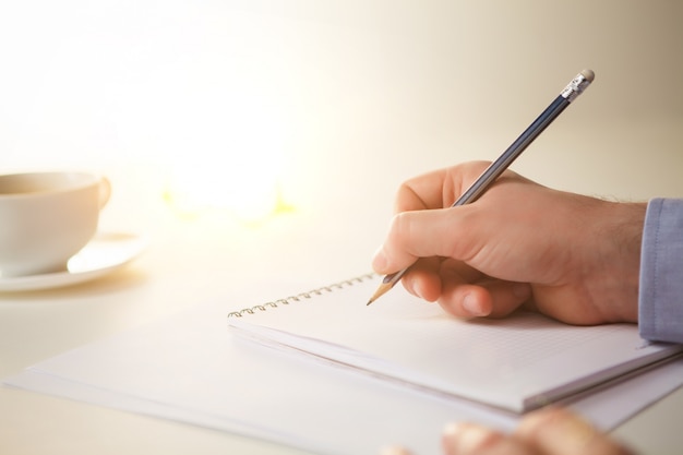 male hand with a pencil and a cup