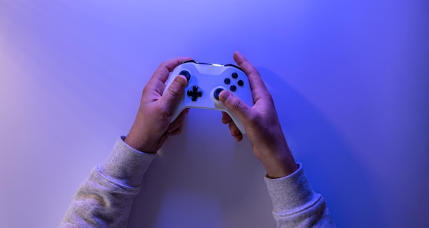 Male hands hold a gamepad on a blue background copy space