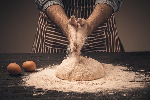 Male hands knead the dough.