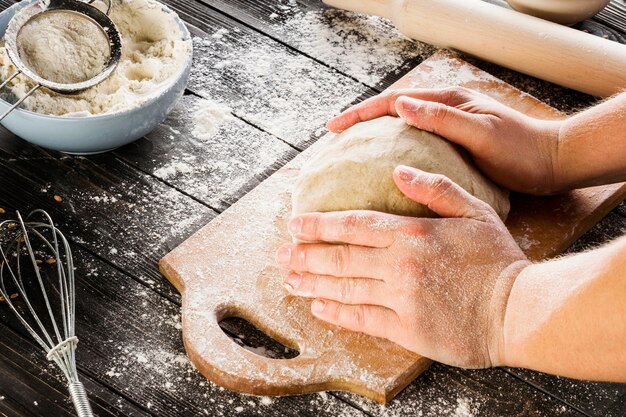 Male hands kneading dough on sprinkled with flour table