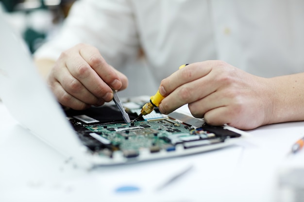 Foto gratuita mani maschii che riparano computer portatile