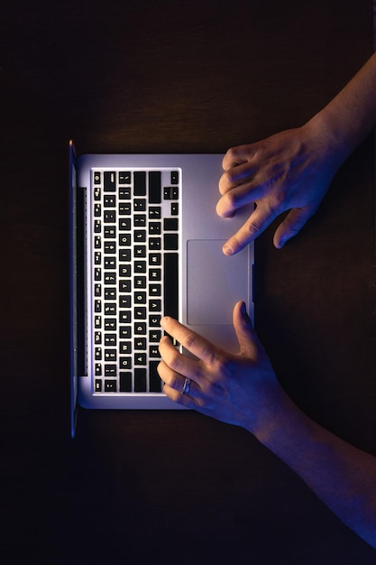 Free photo a male hands working on the laptop at night top view