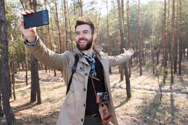 森の中の携帯電話でselfieを取って男性ハイカー